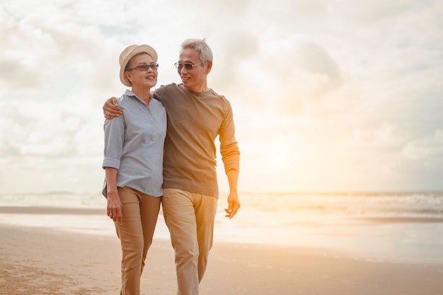 Senior koppels omarmen het zonsondergangstrand, plannen levensverzekeringen met het concept van gelukkig pensioen.