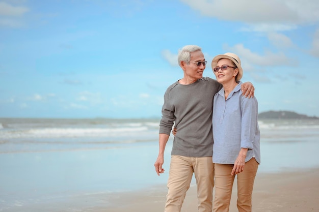 Senior koppels omarmen het zonsopgangstrand, plannen levensverzekeringen met het concept van gelukkig pensioen.