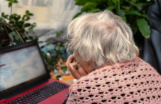 Пожилая женщина за компьютером Пожилая женщина учится за ноутбуком