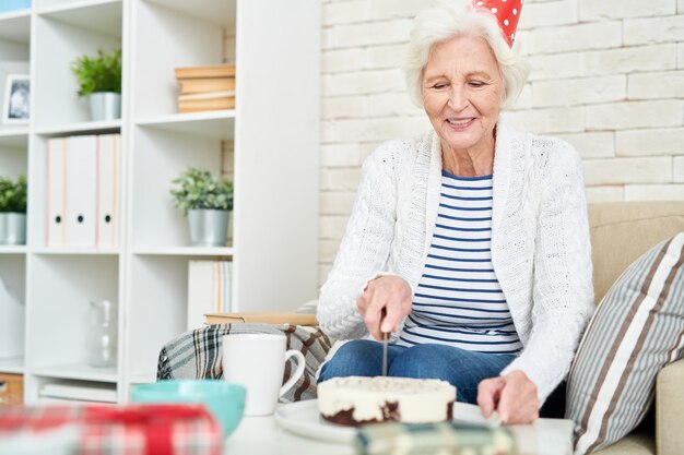 誕生日ケーキを切るシニア女性