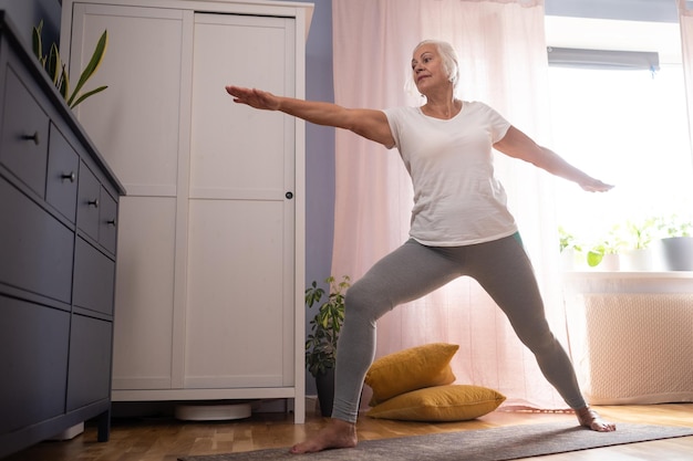 Senior lady doing yoga asana at living room