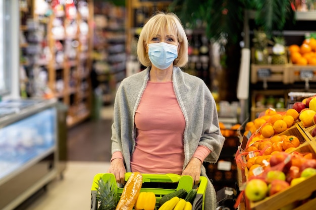 スーパーマーケットで食料品をやっているフェイスマスクのシニア女性