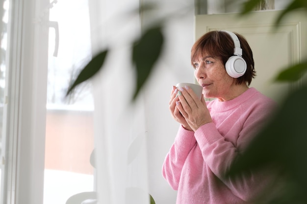 senior lady in pink sweater finds joy in coffee and tunes happiness at any age