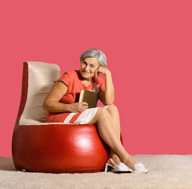 Senior lady reading book sitting on armchair