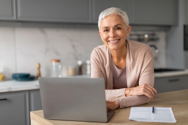 Senior lady using laptop working online engaging in gadgets indoor