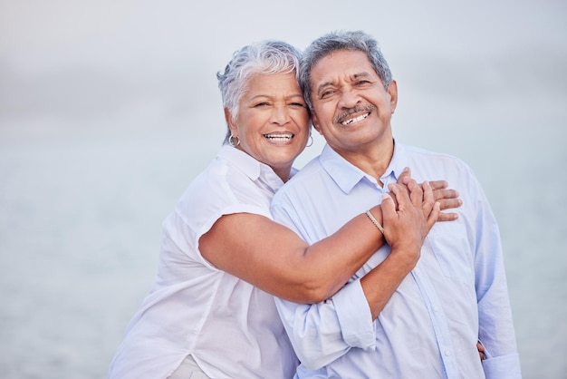 Senior love hug and portrait couple on beach in trust hug security and safety on retirement holiday vacation or break Happy couple people smile and elderly man and woman bonding close together