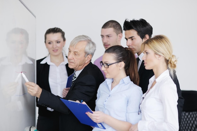 Senior male business man giving a presentation at a  meeting at modern light office on a table board