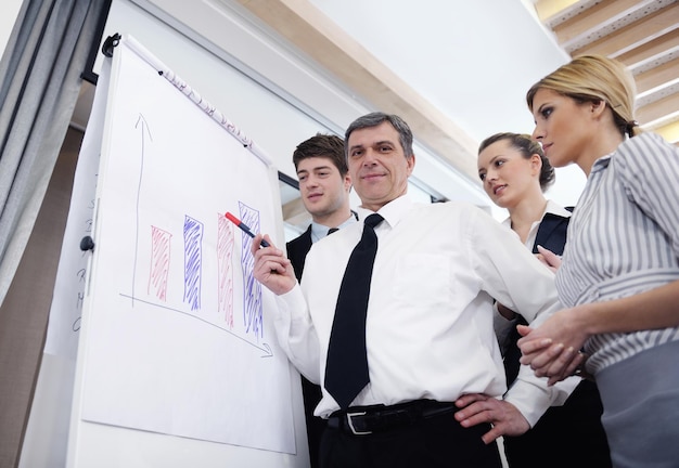 Senior male business man giving a presentation at a  meeting at modern light office on a table board