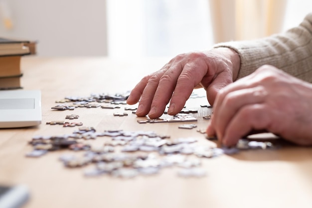 Mani maschili senior che lavorano su un puzzle a casa