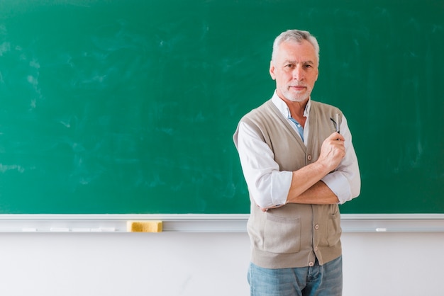 Photo senior male professor standing against green chalkboard