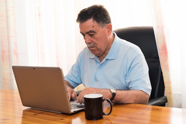 Senior man aan het werk op laptop. Neutrale expressie.