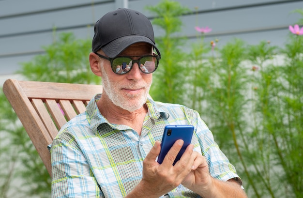 Senior man in a baseball cap portrait using smartphone