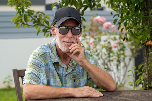 Senior man in baseball cap with sunglasses relaxing in the garden