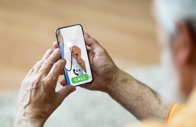 Senior man calling doctor on smartphone while sitting at home