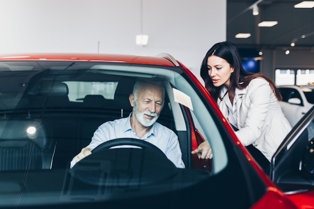 Senior man choosing a new car at car showroom