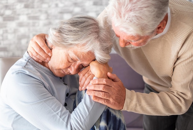 Senior man comforting his depressed illness wife unhappy elderly woman at home Ourmindsmatter