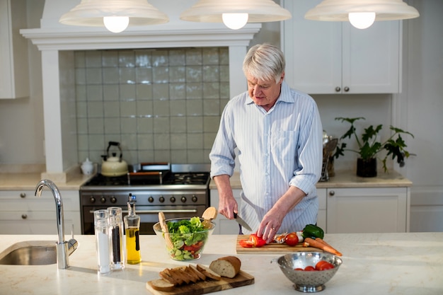 Senior man cutting vegetables for salad