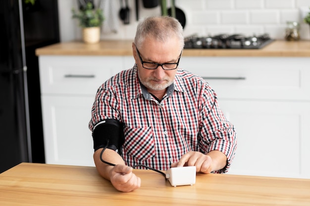 Senior man die een medisch hulpmiddel gebruikt om de bloeddruk te meten