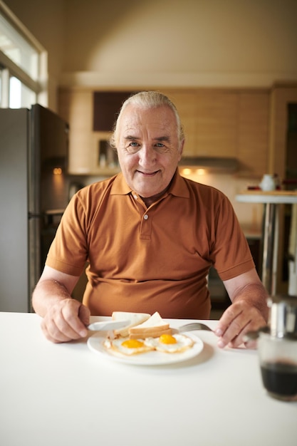 Senior man die gebakken eieren eet