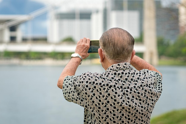 Senior man die smartphone gebruikt om foto's en video te maken