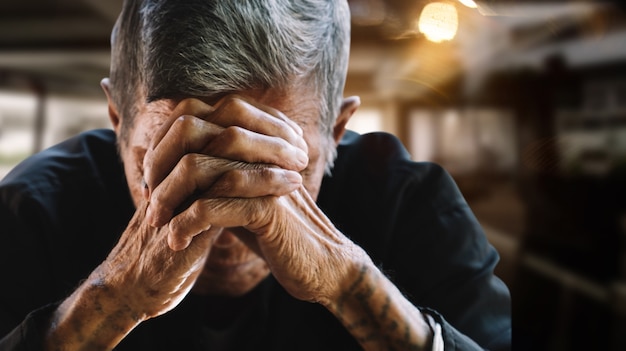 Senior man die zijn gezicht bedekt met zijn handen. Depressie en angst Kopieer de ruimte.