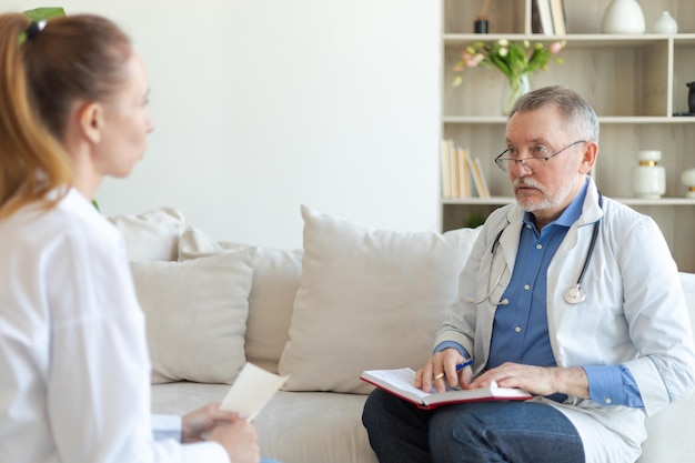 Senior man doctor examining yound woman in doctor office or at home girl patient and doctor have con