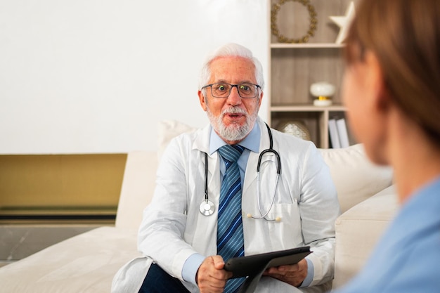 Senior man doctor examining young woman in doctor office clinic or at home girl patient and doctor