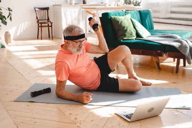 Senior man doing fitness exercise at home with dumbbells elderly people and wellness health concept