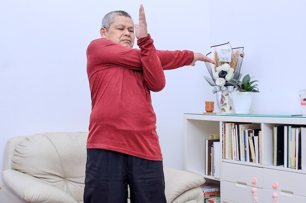 Senior man doing hand stretching and exercise at home