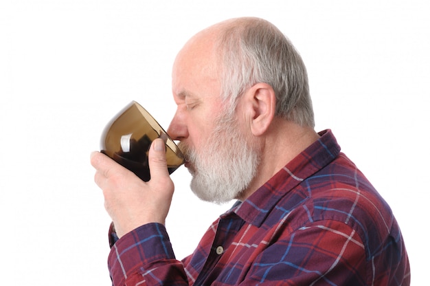 Senior man drinking from cup.