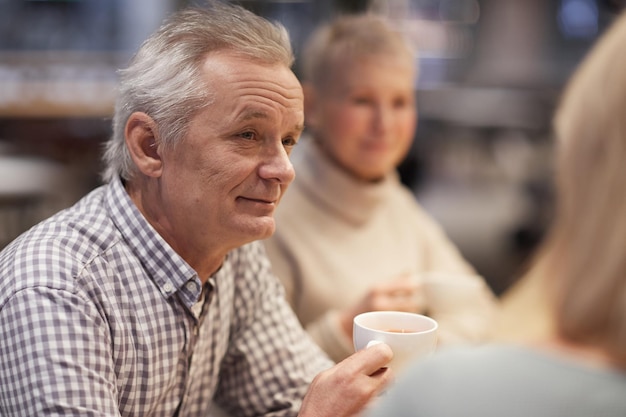 Senior man drinking tea with friends