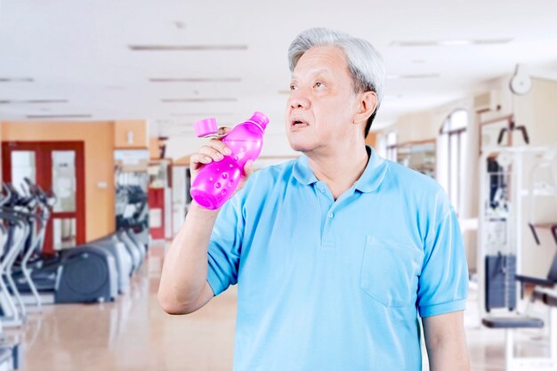 フィットネスセンターで水を飲む年配の男性