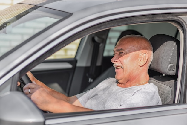 Uomo anziano alla guida di un'auto, guardando la strada. concetto di guida.