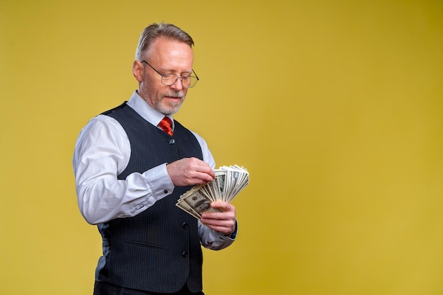 Старший мужчина зарабатывает деньги Серьезный мужчина смотрит на доллары Счастливый человек наслаждается концепцией денег