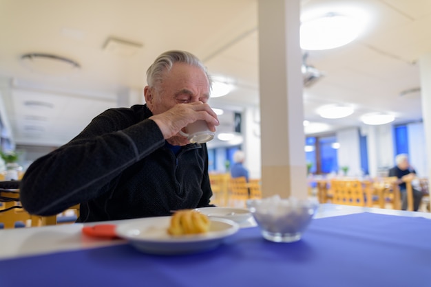 特別養護老人ホームの食堂で食べる年配の男性