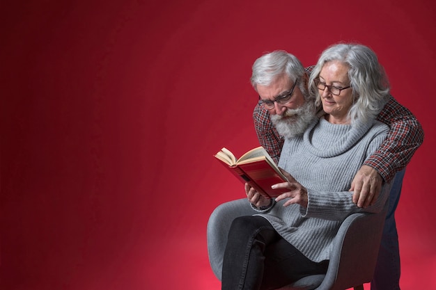 사진 빨간색 배경에 책을 읽고 그녀의 아내를 포용하는 수석 남자