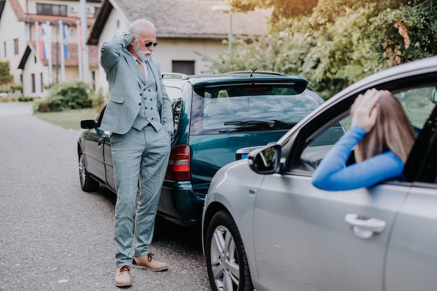 Senior man en jonge vrouw ruzie na auto-ongeluk.