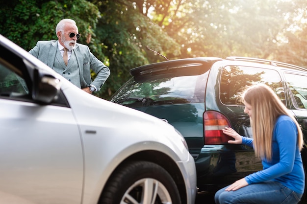 Senior man en jonge vrouw ruzie na auto-ongeluk.