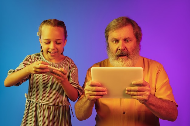 Senior man en kleindochter op neon achtergrond