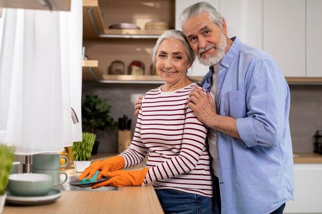 Senior man en vrouw afwassen in de keuken en glimlachen naar de camera