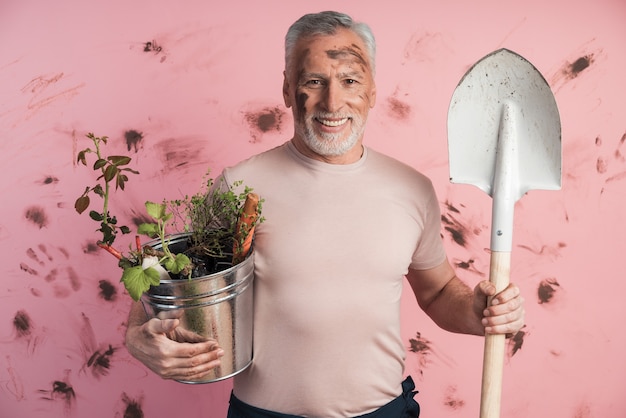 Senior man, gardener with a shovel and a bucket in his hands