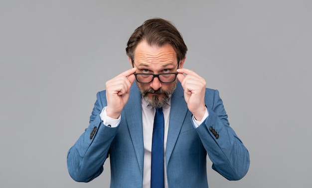 Senior man in glasses look on grey background, eyesight.