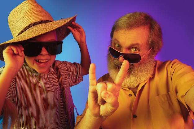 Senior man and granddaughter on neon background