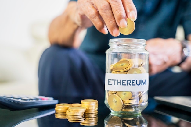 Senior man hand saving Ethereum coins in glass jar