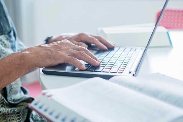 Senior man handen typen op laptop in de bibliotheek