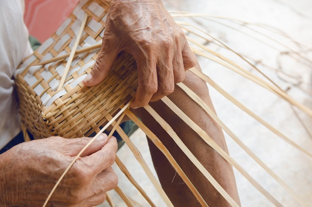 Senior man hands manually weaving bamboo.