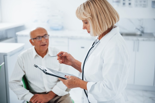 年配の男性は、女性医師によるクリニックでの相談を受けています。