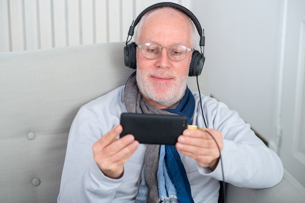 Senior man in headphones listening to music at home