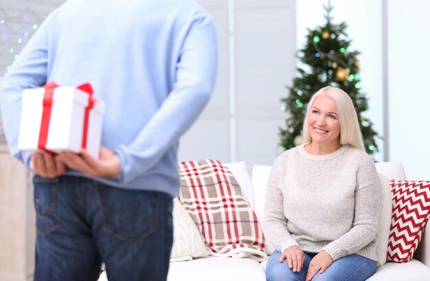 自宅で妻へのクリスマスプレゼントを隠す年配の男性