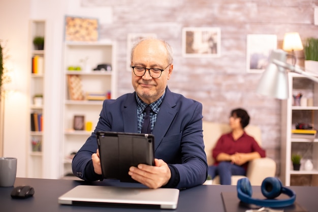 居心地の良い家で最新のデジタルタブレットを使用している60代の年配の男性